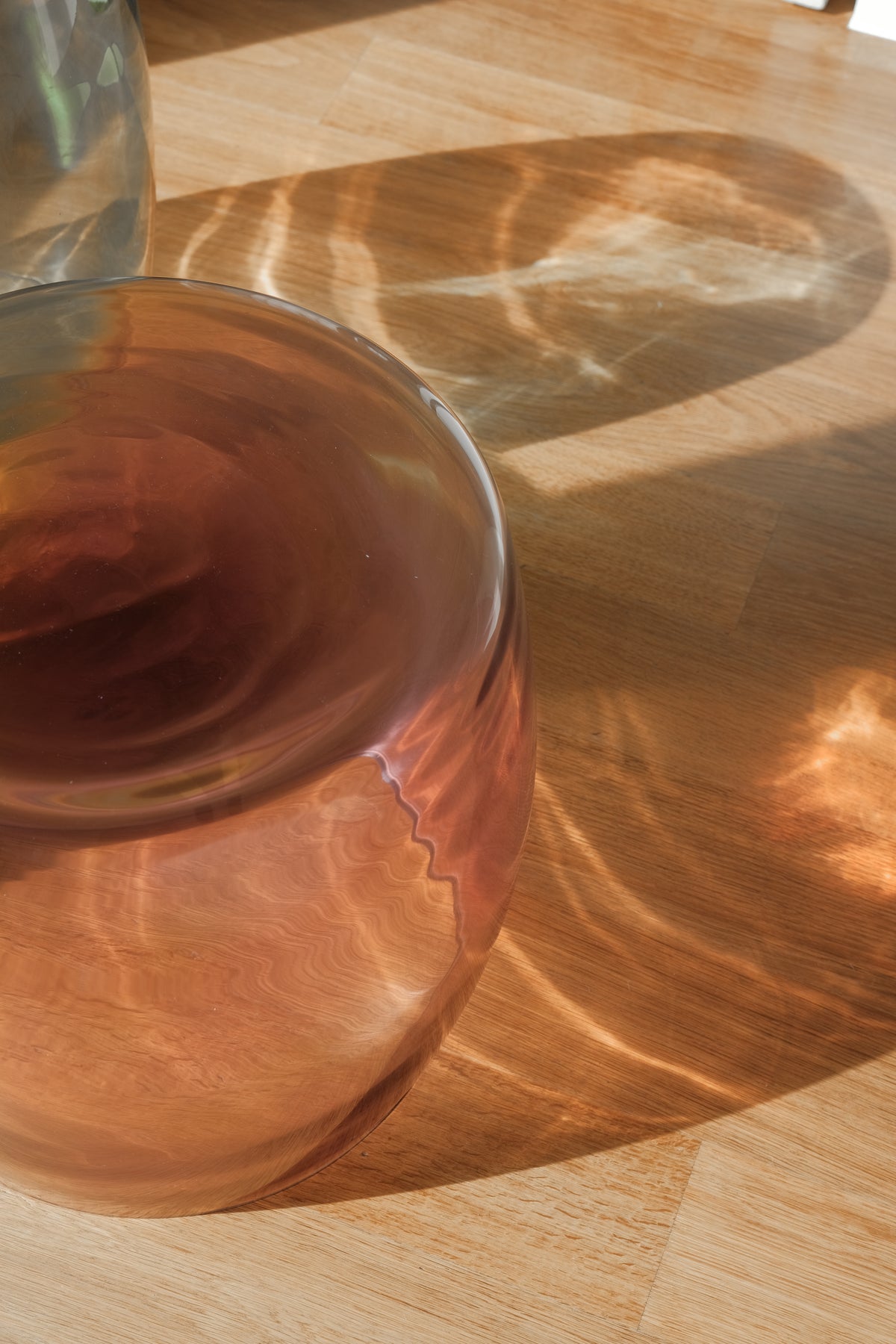 Close-up of Tavolino Ametista 40 showing internal movement, natural colour gradients, and molten-glass light refractions on a wooden floor.